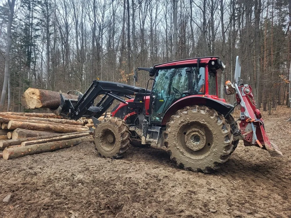 Traktor s čelným nakladačom pri sklade dreva
